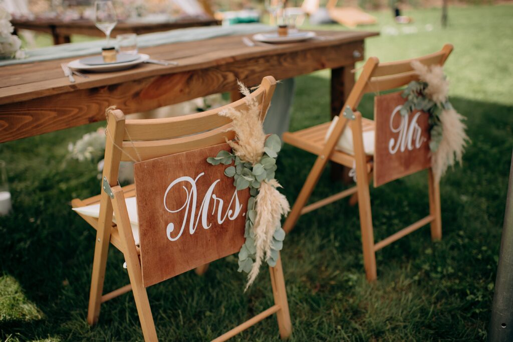Outdoor wedding ceremony at Texas venue with pond view, wooden chairs, floral arch, sunny sky