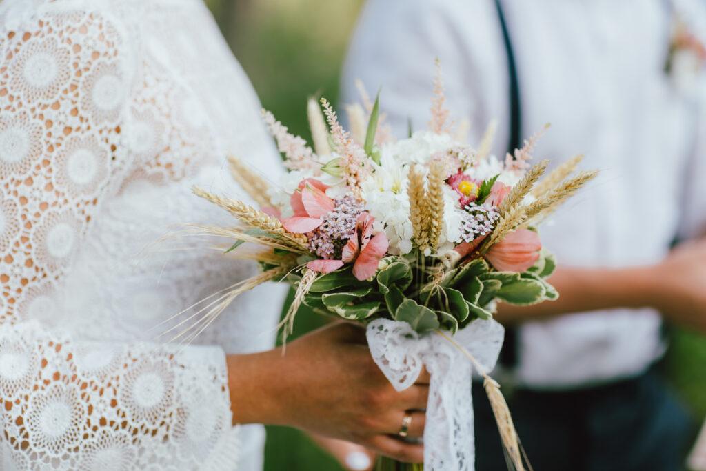 Crop photo of bride young woman with the boho style bouquet with groom on wedding ceremony in the forest